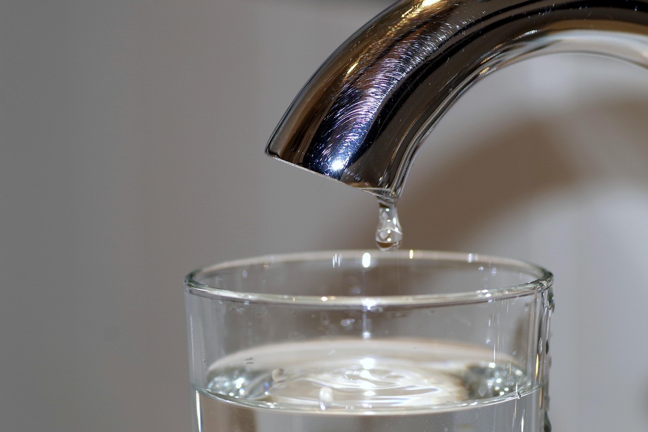 Foto Wasserhahn mit einem Tropfen und ein Wasserglas