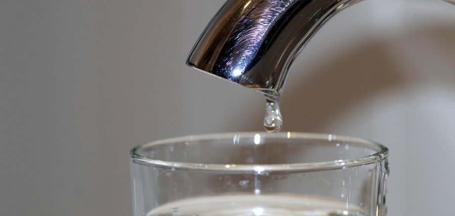 Foto Wasserhahn mit einem Tropfen und ein Wasserglas
